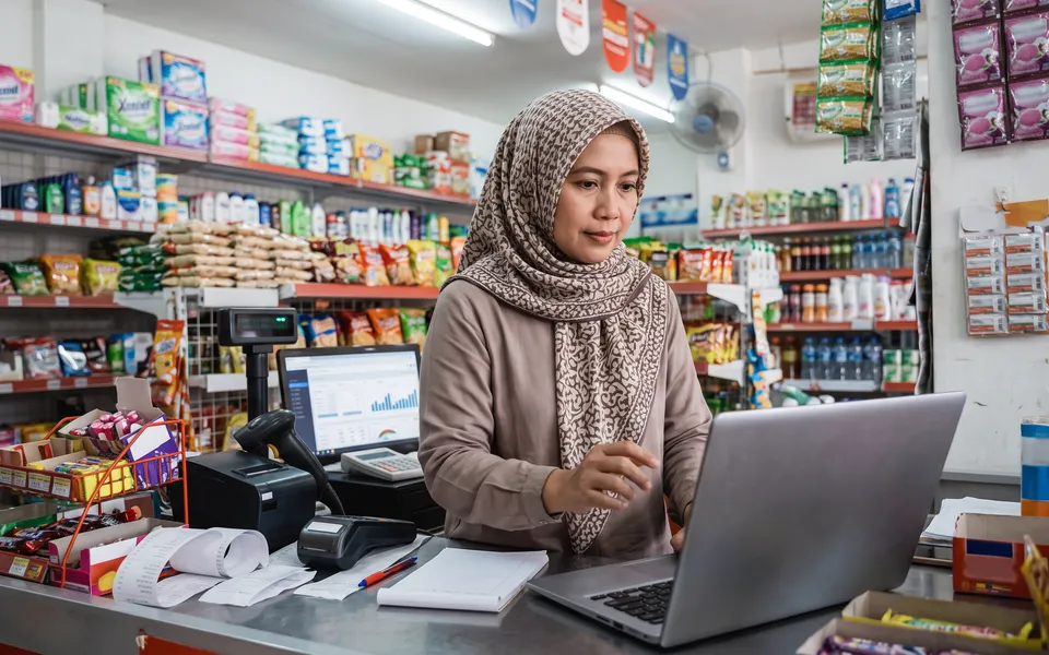 Pemilik toko memantau stok dan penjualan di laptop